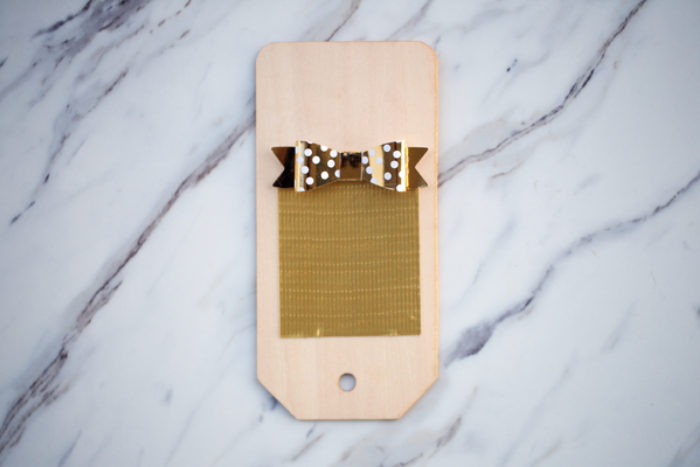 A wooden gift tag with gold Duck Tape on it.