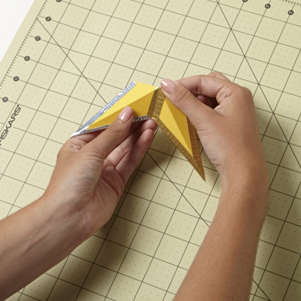 After creating another piece identical to the one taped together in the previous step, tape them together at the top of the diamond shape so that you have two of the the star's points